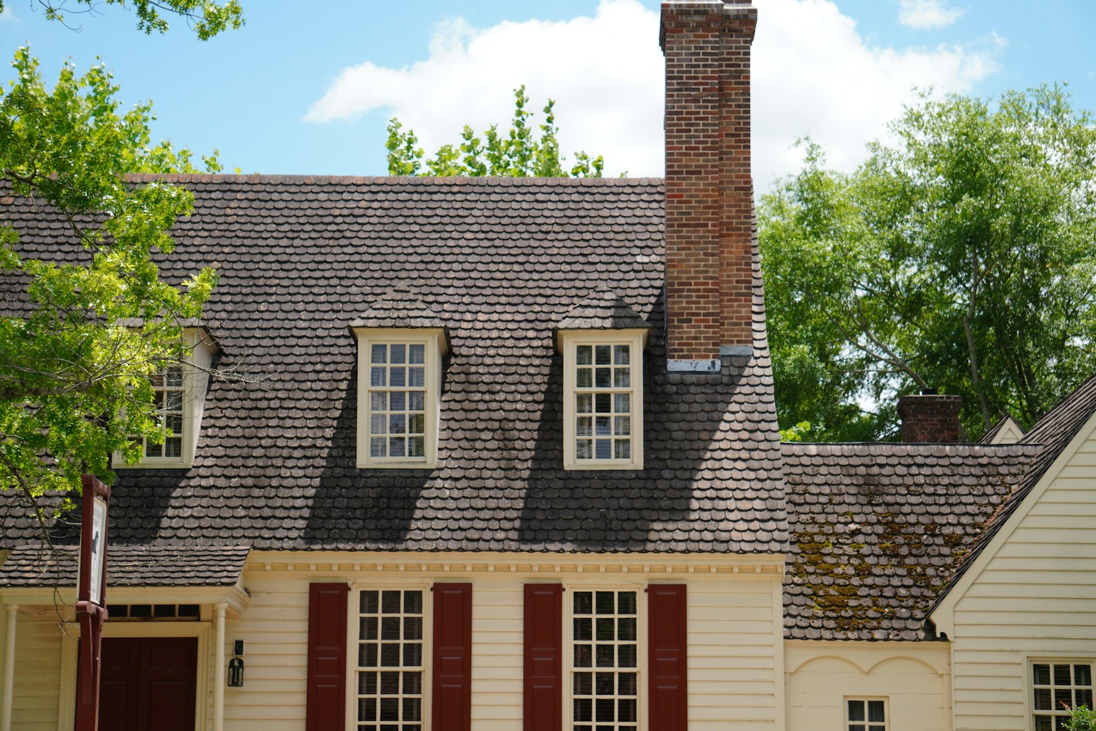 a white house with red shutters and a chimney